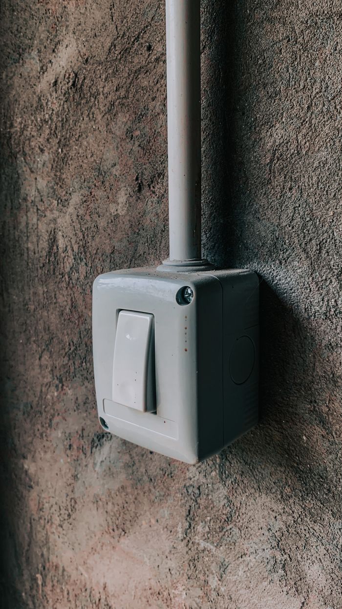 Close-up of a switch box mounted on a textured concrete wall in soft light.