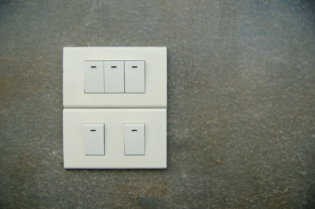 Minimalist photo of white electrical rocker switches on a textured stone wall background.