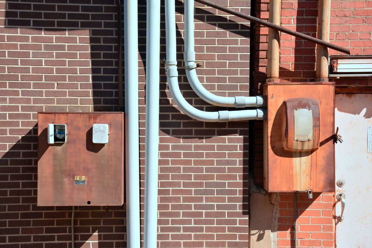 mobile-02 Close-up of industrial utility boxes and piping on a brick wall in Texarkana, Texas.