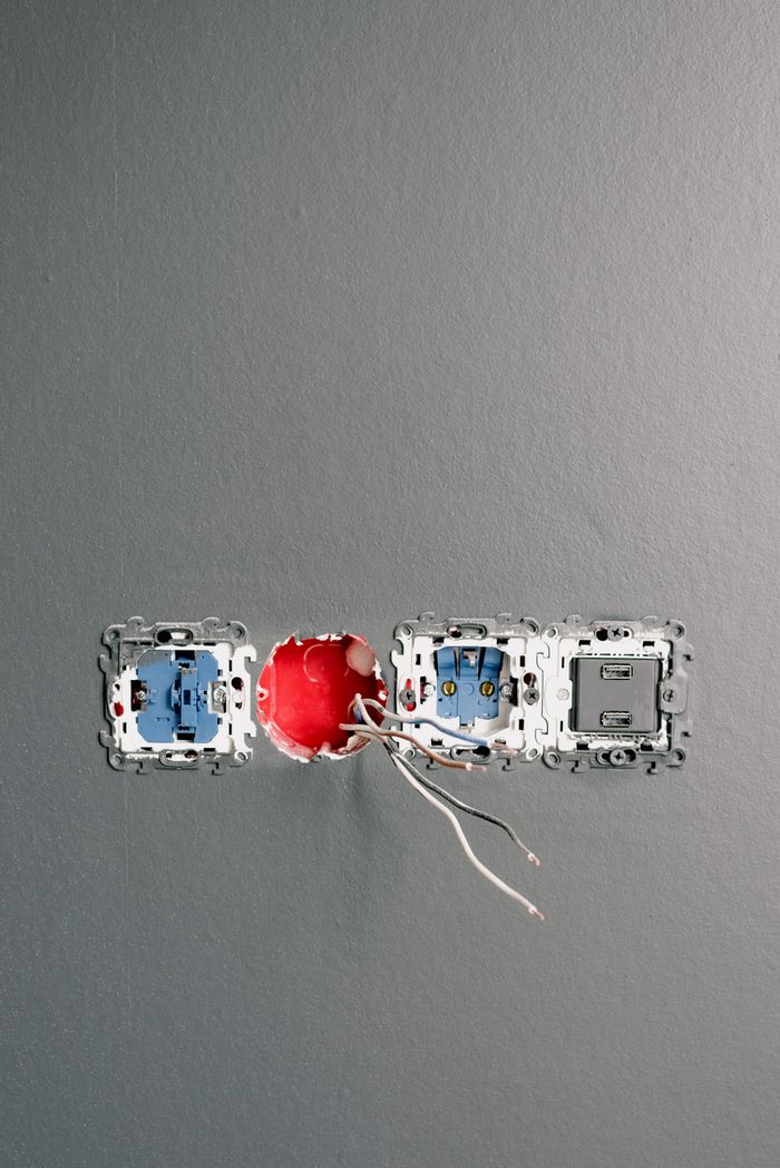 brand-01 Sockets with wires and bolts on gray painted wall at home during construction